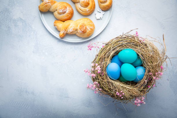 Ostereier im Nest mit süßen Brötchen aus Hefeteig in Form eines Osterhasen 